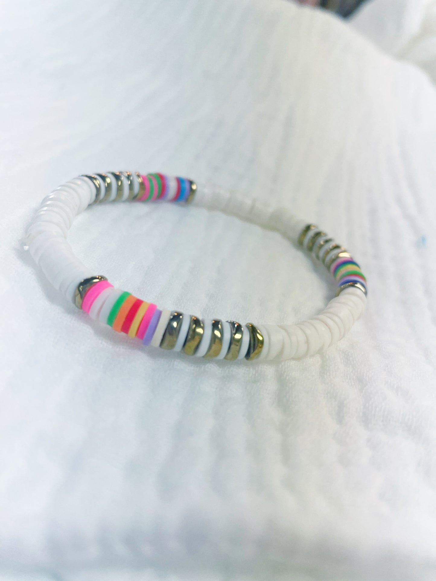 White soft rubber disc beaded stretch bracelet with a few multi colored and gold disc beads
