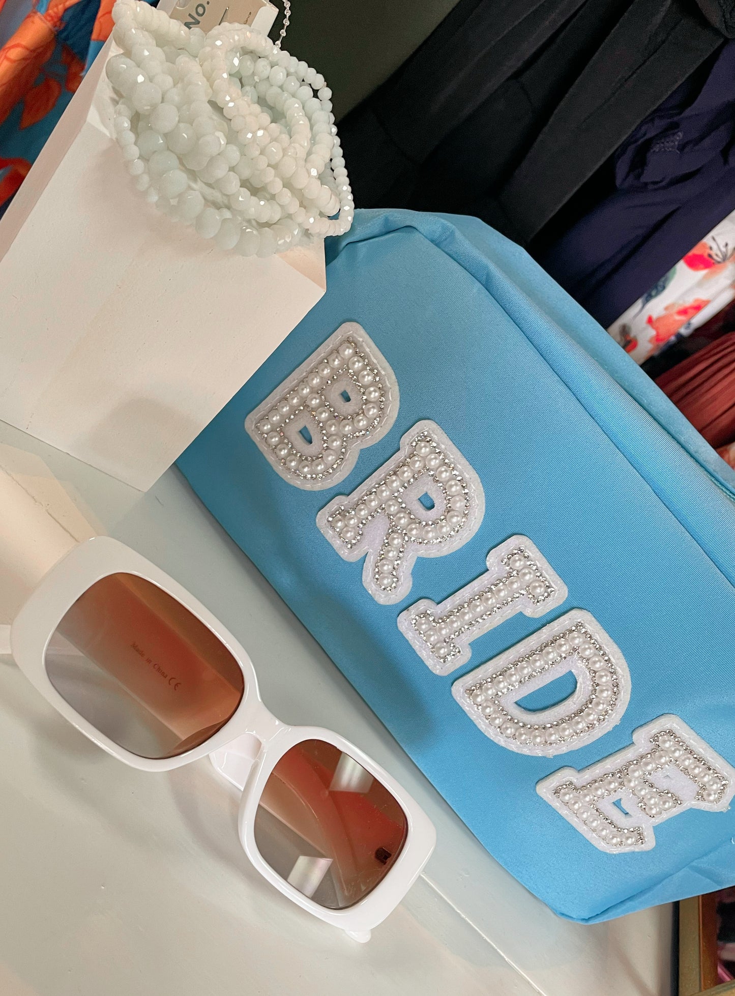 Tiffany blue zippered nylon pouch with the word 'bride' embroidered in white varsity letters on the outside of the pouch.