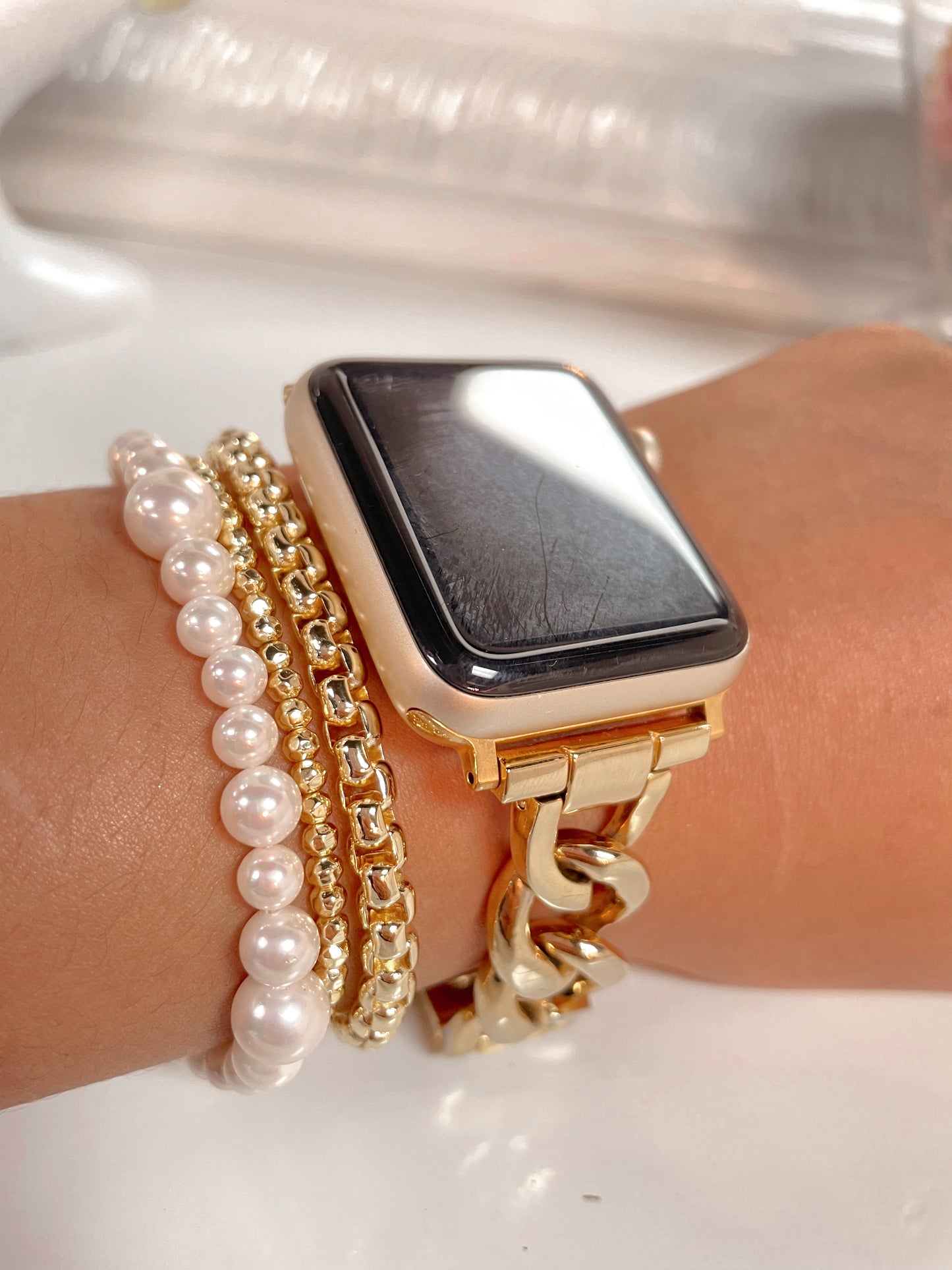 Pearl bracelet with gold clasp paired with other gold bracelets