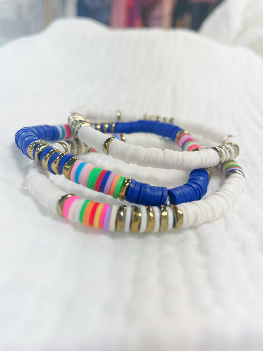 Cobalt blue, multi white, and all white soft rubber disc beaded stretch bracelet with a few multi colored and gold disc beads