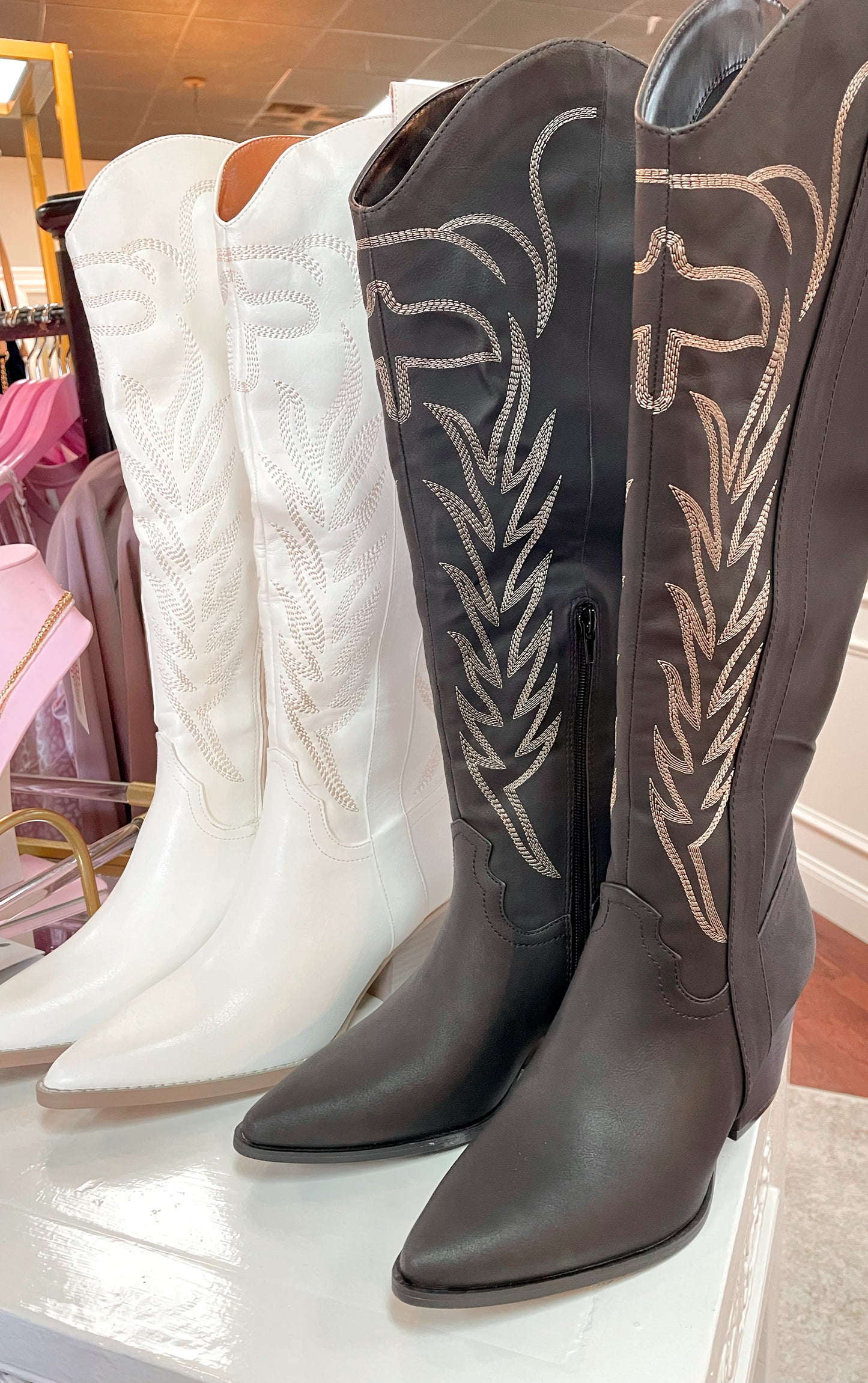 Tall black cowboy boots with embroidered detailing and tall white cowboy boots with embroidered detailing